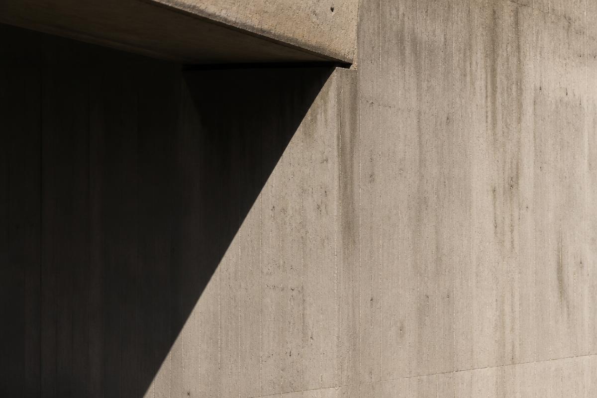 Brutalist concrete facade cut by a hard diagonal shadow